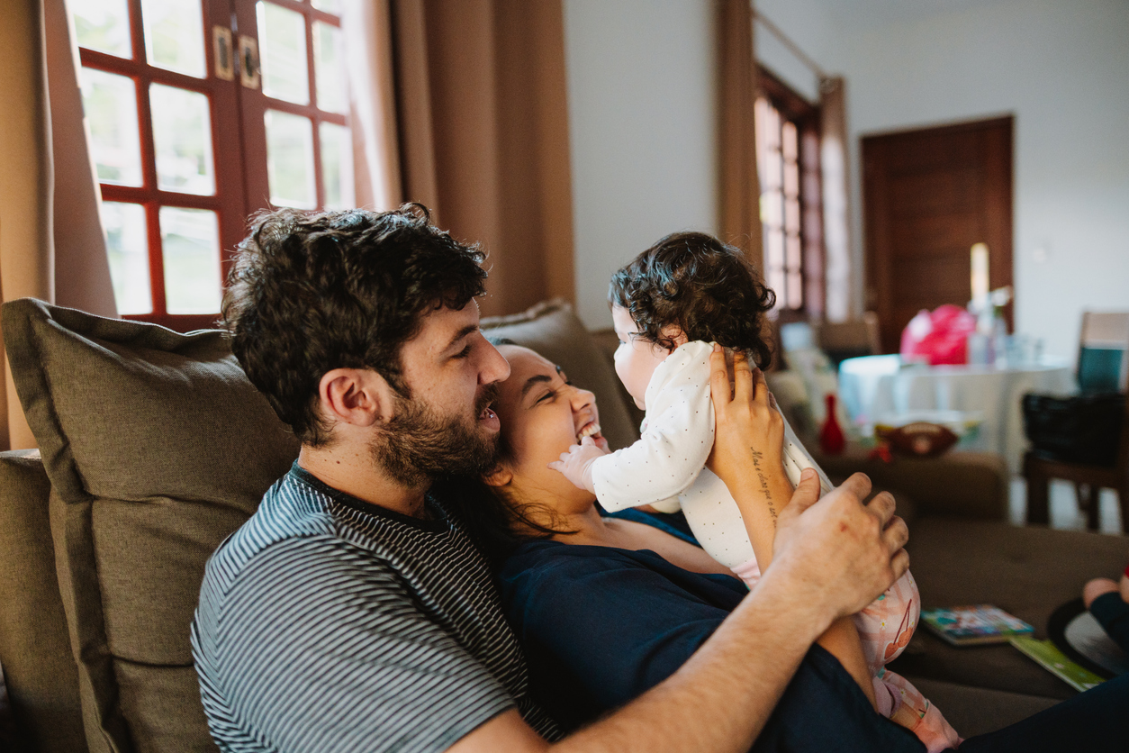 Father and mother playing with toddler on the sofa